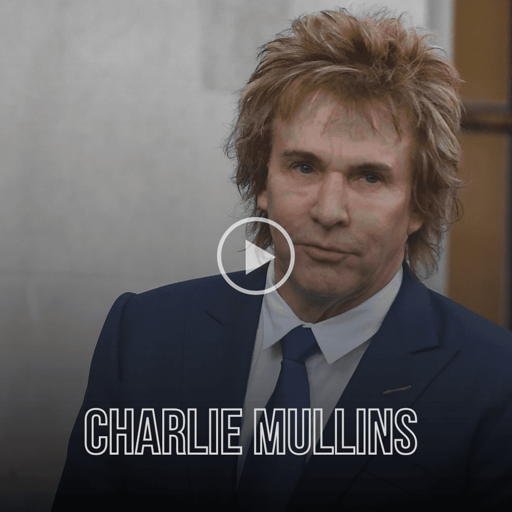 Charlie Mullins with his signature feathered hair, wearing a navy suit and blue tie.